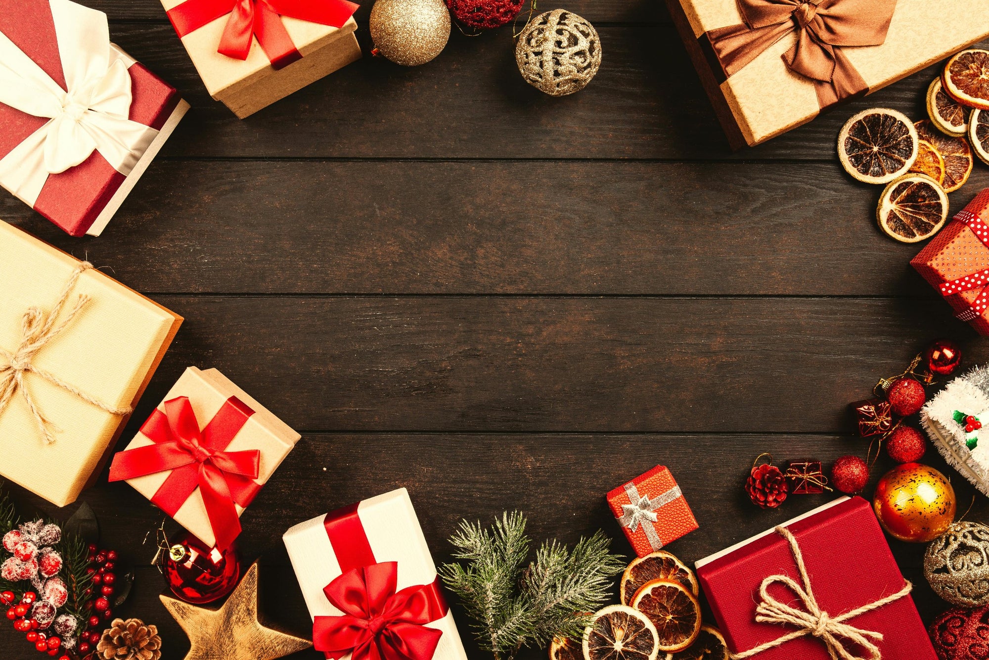 Christmas gifts and ornaments in circle over dark wooden floor