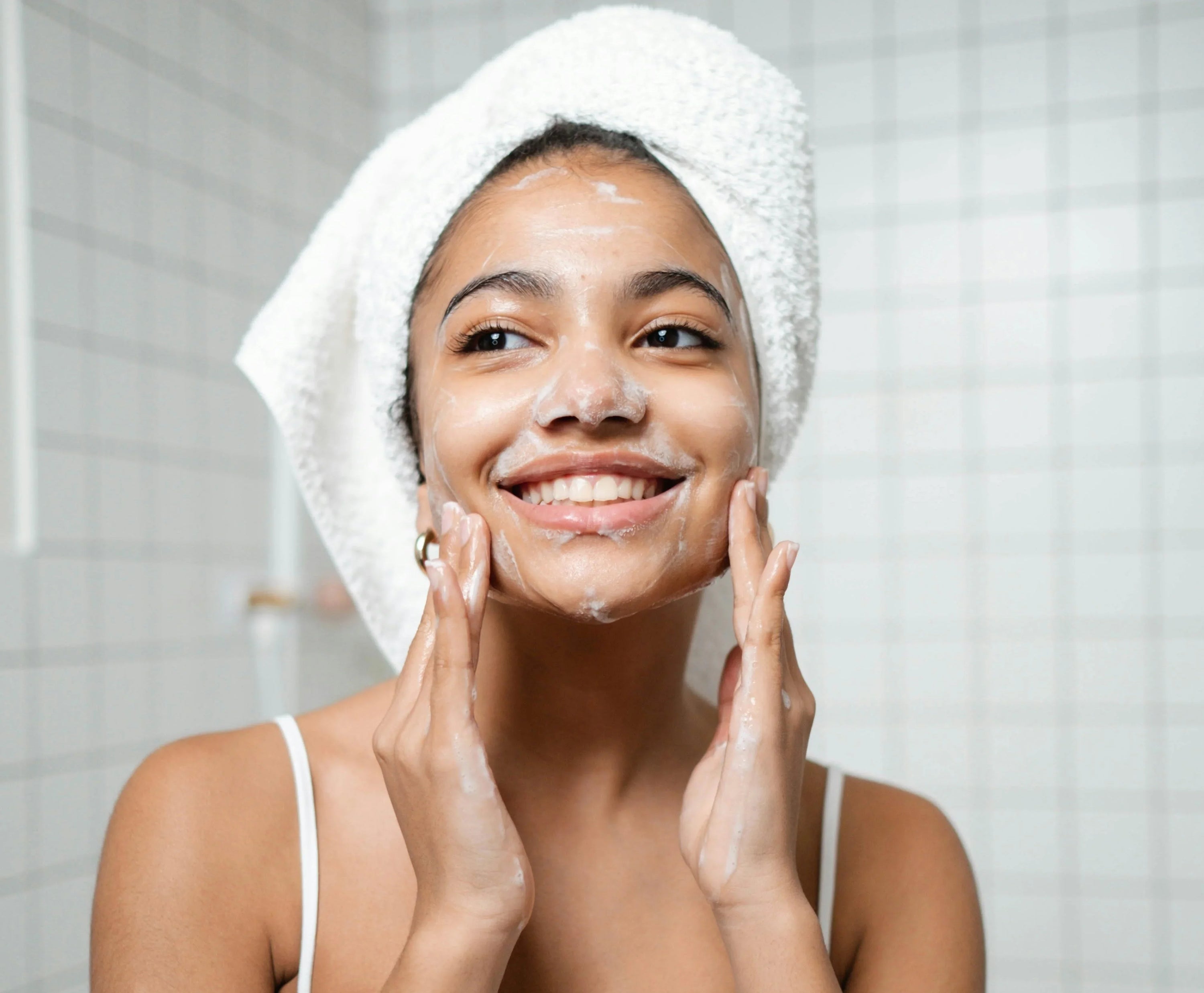 Woman applying cleanser to face while smiling
